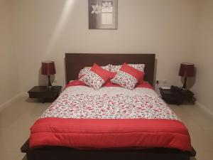 a bedroom with a large bed with red sheets and two lamps at LINDA SUITE Puerto Santa Ana GUAYAQUIL in Guayaquil