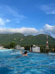 a man in a swimming pool with mountains in the background at Tuấn Ninh Hotel II in Con Dao