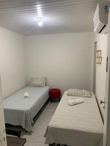 um quarto com duas camas e uma cadeira vermelha em Pousada Aconchego em Aracaju