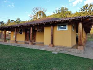 una pequeña casa amarilla con techo en Casas Bueno en Camanducaia