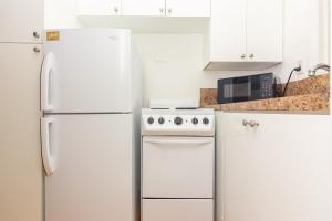 a white kitchen with a refrigerator and a stove at Studio Apartment Fort Lauderdale - 5 minutes walk to Las Olas Beach in Fort Lauderdale