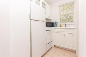 a kitchen with white cabinets and a white refrigerator at Studio Apartment Fort Lauderdale - 5 minutes walk to Las Olas Beach in Fort Lauderdale