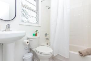 a white bathroom with a toilet and a sink at Apartment Fort Lauderdale - 5 minutes walk to Las Olas Beach in Fort Lauderdale