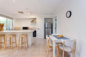 cocina con mesa, sillas y nevera en Suburban Villa, en Perth