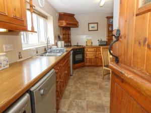 a kitchen with wooden cabinets and a sink at Porth Awyr in Llangwnadl