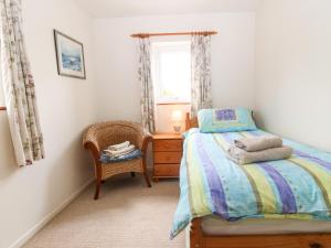 a bedroom with a bed and a chair and a window at Porth Awyr in Llangwnadl
