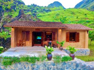 a small house in front of a mountain at H'mong Village Resort in Ha Giang