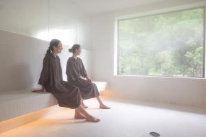 two women sitting on a bench looking out a window at Urari Takeo Garden Terrace Spa Resorts in Takeo