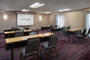 a conference room with tables and chairs and a projection screen at Courtyard Sacramento Rancho Cordova in Rancho Cordova