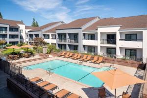 a pool at a hotel with chairs and umbrellas at Courtyard Sacramento Rancho Cordova in Rancho Cordova