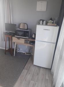 a kitchen with a refrigerator and a table with a microwave at Country View Sleepout in Hamilton