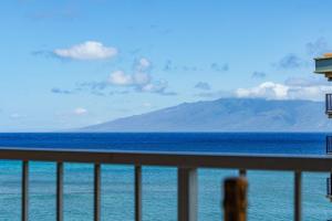 una persona parada en un balcón con vistas al océano en Royal Kahana 702 Studio Condo, en Kahana