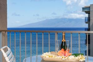 una mesa con una botella de champán y flores en el balcón en Royal Kahana 702 Studio Condo, en Kahana
