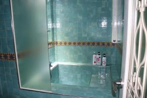 a blue tiled bathroom with a shower with a glass door at Hotel Marigold in Incheon