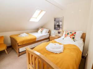 duas camas num pequeno quarto com lençóis amarelos em The Barn em Northallerton