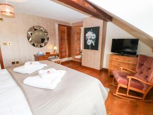 a bedroom with a bed and a chair and a television at The Barn in Northallerton