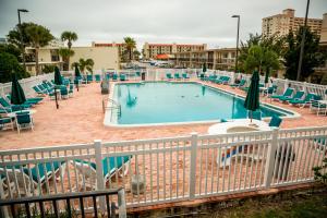 a large swimming pool with chairs and a fence at Ocean Landings Resort in Cocoa Beach