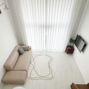 un salon avec un canapé et une télévision dans l'établissement Rooftop Moonlight Pension, à Gangneung