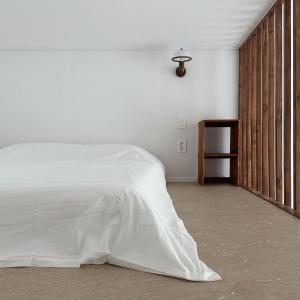ein Schlafzimmer mit einem weißen Bett und einer Holzwand in der Unterkunft Rooftop Moonlight Pension in Gangneung