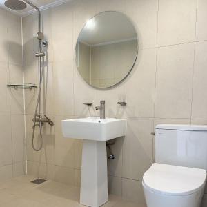 a bathroom with a sink and a toilet and a mirror at Rooftop Moonlight Pension in Gangneung