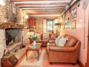 a living room with leather furniture and a stone fireplace at Hadcroft Cottage in Chipping Campden