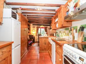 een keuken met houten kasten en een witte koelkast bij Hadcroft Cottage in Chipping Campden