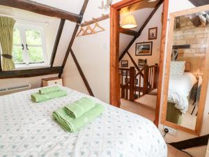 a bedroom with a bed with two green towels on it at Hadcroft Cottage in Chipping Campden