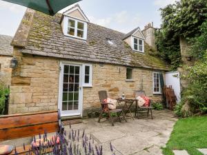 a patio with a table and chairs in front of a cottage at Hadcroft Cottage in Chipping Campden