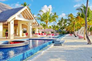 a resort swimming pool with palm trees and a resort at Kandima Maldives in Kudahuvadhoo