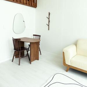 una mesa y una silla en una habitación con espejo en Rooftop Moonlight Pension en Gangneung