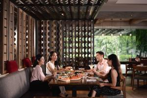 un grupo de personas sentadas alrededor de una mesa en un restaurante en Bangkok Marriott Marquis Queens Park en Bangkok