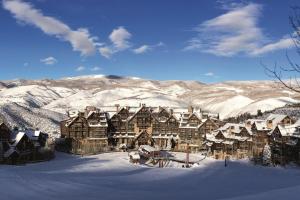 a large lodge in the snow with snow covered mountains at The Ritz-Carlton, Bachelor Gulch in Beaver Creek