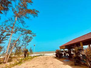 a building next to a beach with a tree at 24 Gold Homestay in Phan Thiet