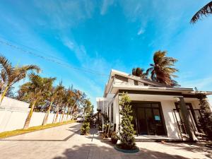 a white building with palm trees on a street at 24 Gold Homestay in Phan Thiet