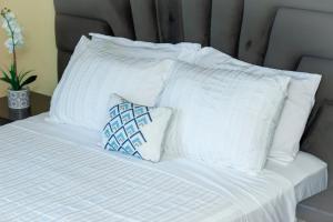 Una cama blanca con almohadas blancas encima. en Acacia Stay, en Lilongwe