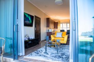 uma sala de estar com uma cadeira amarela e uma mesa em Acacia Stay em Lilongwe