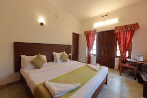 1 dormitorio con 1 cama grande, escritorio y cortinas en Green Shades en Munnar