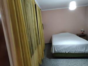 1 dormitorio con cama y cortina amarilla en Departamento Funcional en Guaymallén