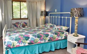 a bedroom with a bed with a floral bedspread at AMITY BEACH BUNGALOW in Amity Point