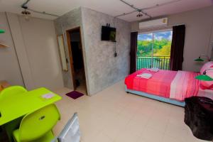 a bedroom with a bed and a green chair and a window at khaolak big bike&room for rent in Khao Lak