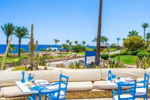 a patio with blue chairs and tables and the ocean at Renaissance Sharm El Sheikh Golden View Beach Resort in Sharm El Sheikh