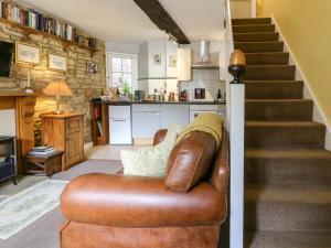 a living room with a leather couch and stairs at Coln Cottage in Stow on the Wold