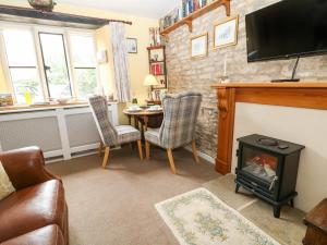 a living room with a fireplace and a table at Coln Cottage in Stow on the Wold