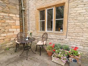 a patio with a table and two chairs and flowers at Coln Cottage in Stow on the Wold