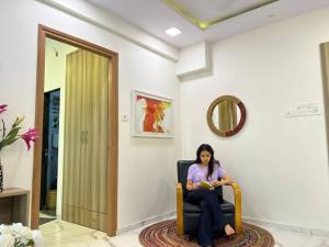 a woman sitting in a chair reading a book at Jastcon, 19th Rd, Khar, Ambedkar Colony by Connekt Homes in Mumbai