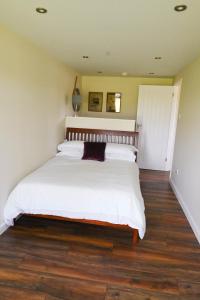 a bedroom with a large white bed with wooden floors at Myrtle in Badsey