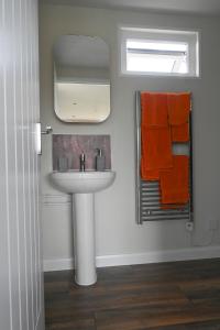 a bathroom with a sink and a mirror and orange towels at Myrtle in Badsey