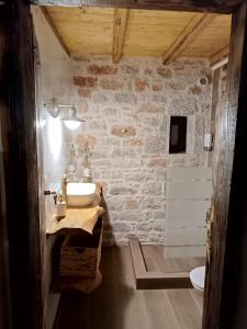 a bathroom with a sink and a stone wall at Suite of Villa Lagkadaki in Agriliá