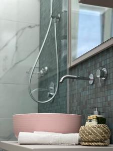 um lavatório de casa de banho com um chuveiro e uma tigela rosa em Jeny Boutique Apartment em Târgu-Mureş