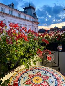a table with flowers on a balcony with a building at Jeny Boutique Apartment in Târgu-Mureş